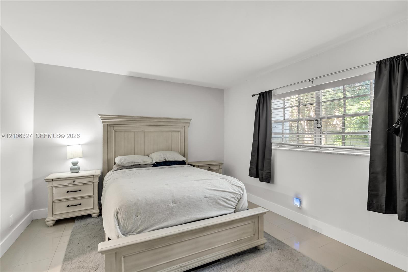 Neutral-toned ceramic tile flooring, horizontal window blinds, and crisp white wall finishes