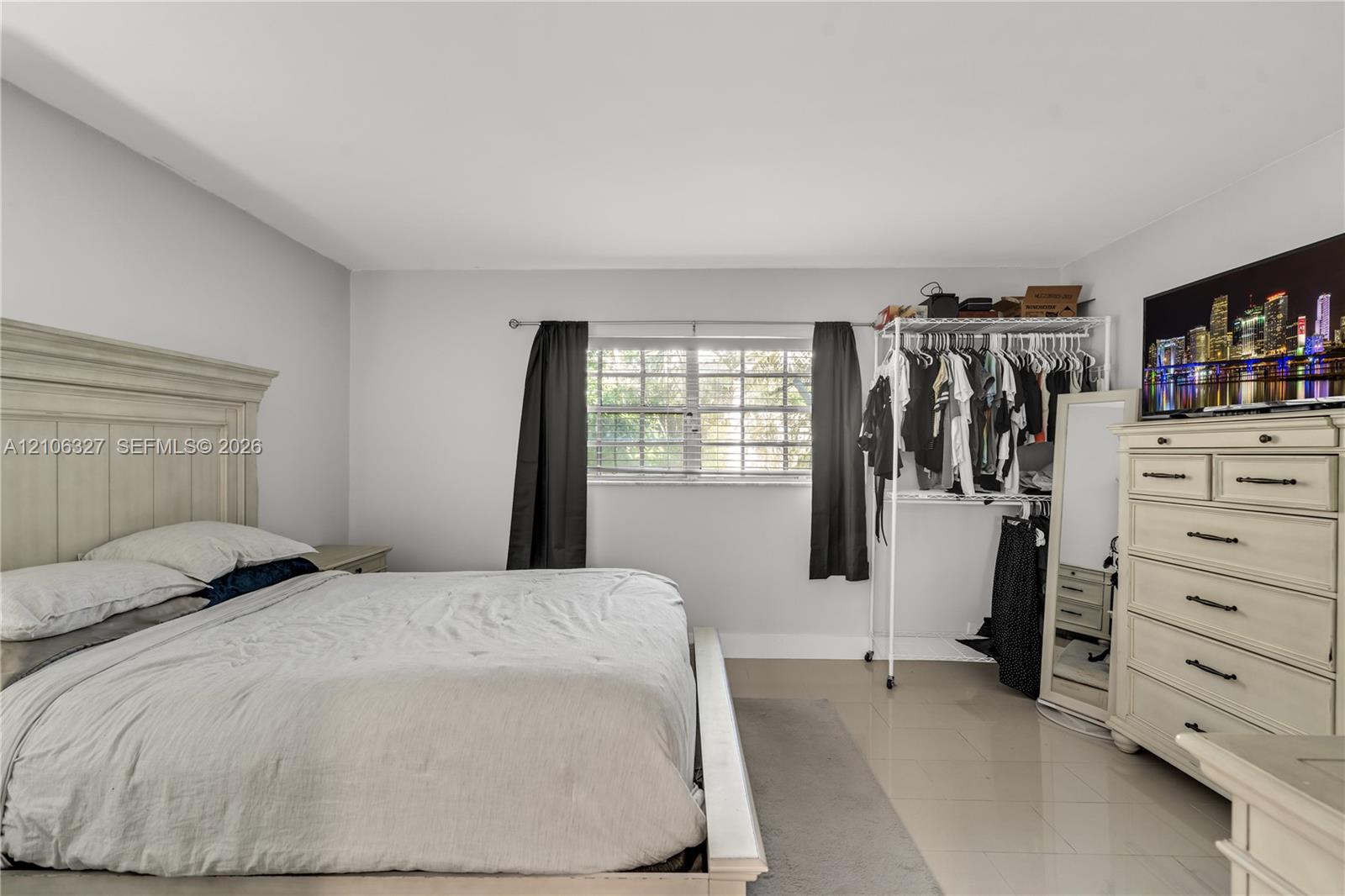 Neutral-toned interior space featuring light-colored tile flooring, smooth walls, and a multi-pane window