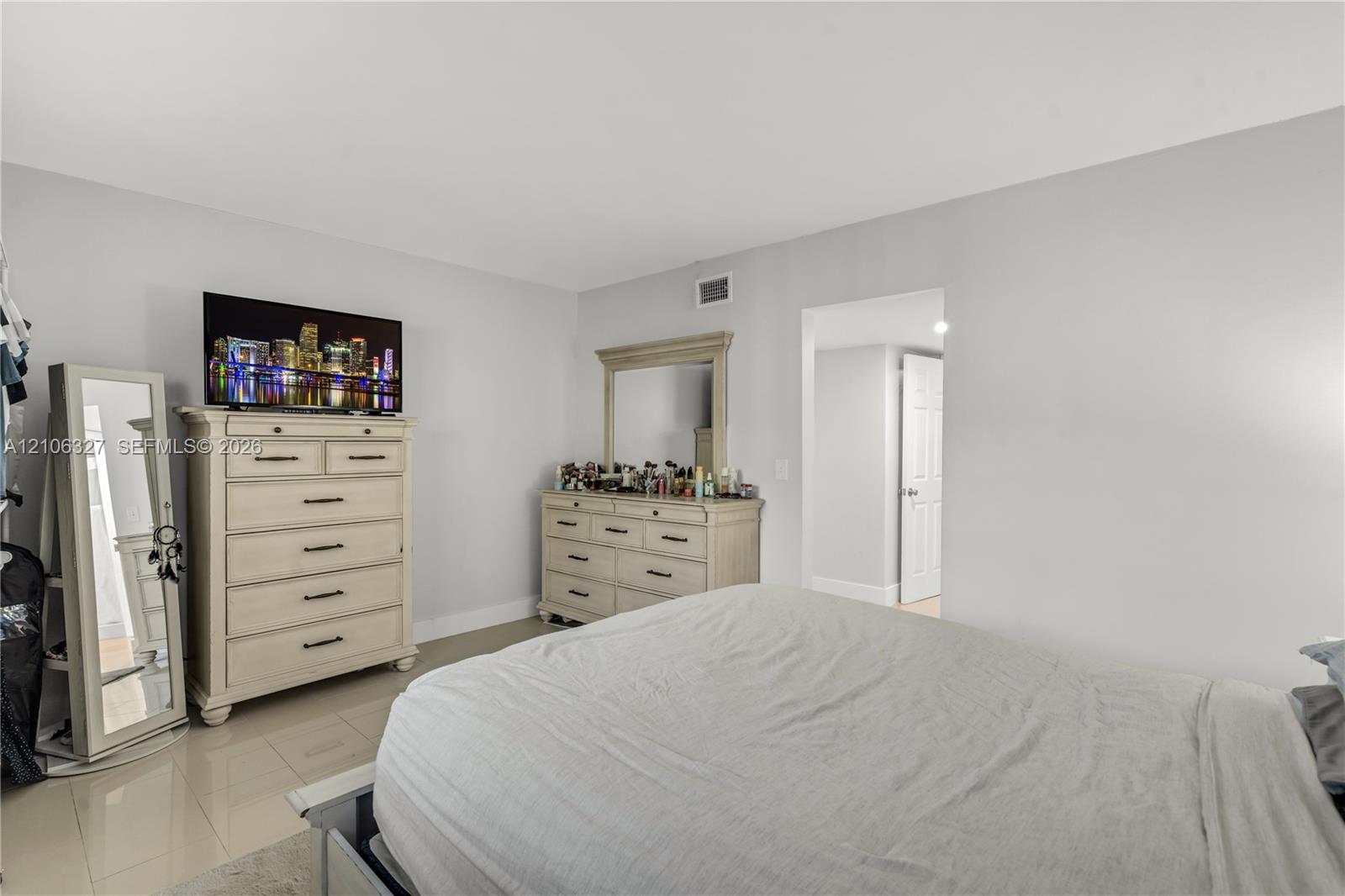 Spacious room featuring neutral wall paint, large-format tile flooring, and a six-panel interior door