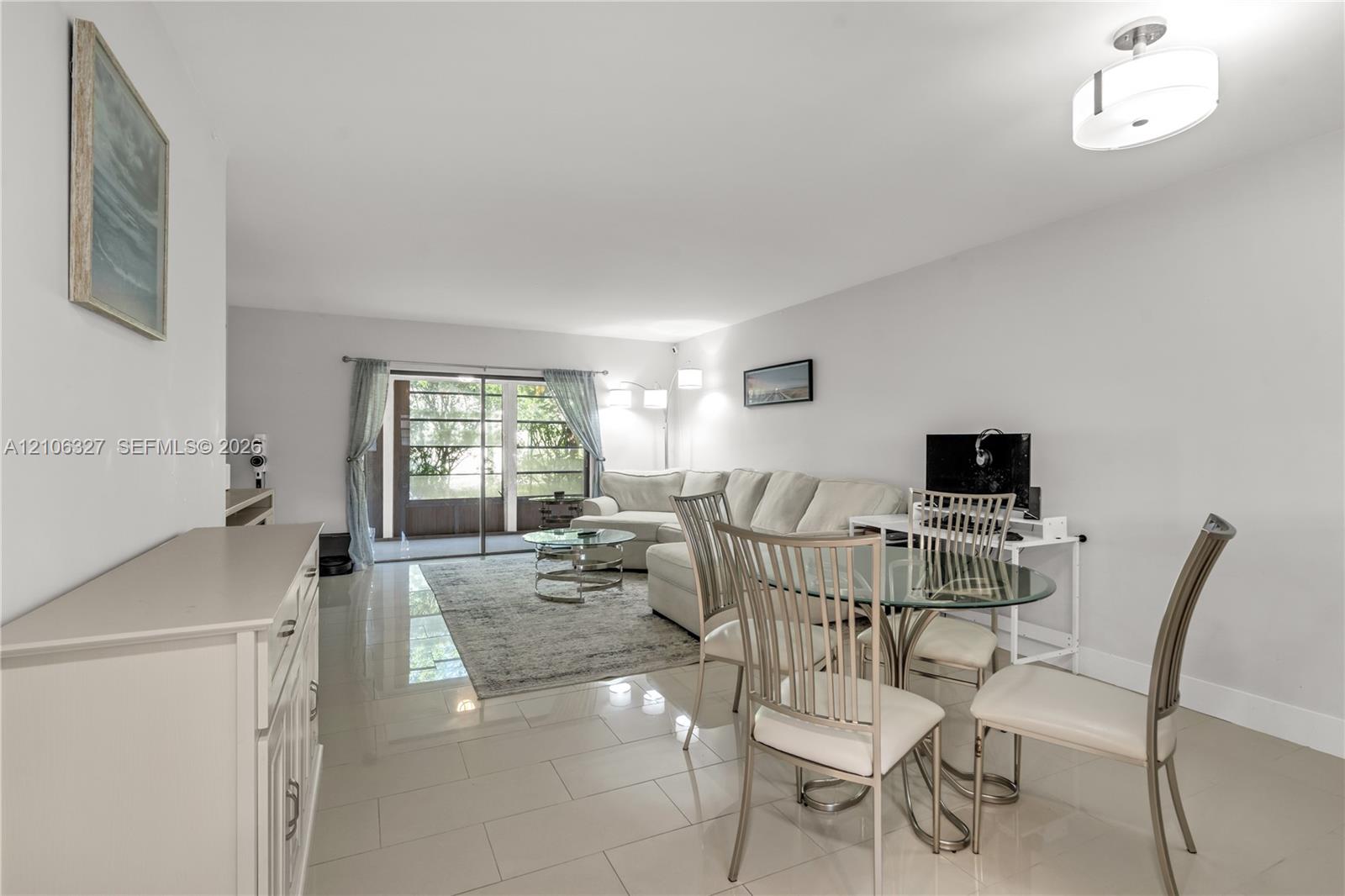 Open-concept area featuring polished tile flooring, neutral wall tones, recessed ceiling lighting, a contemporary drum-style pendant light, and sliding glass doors