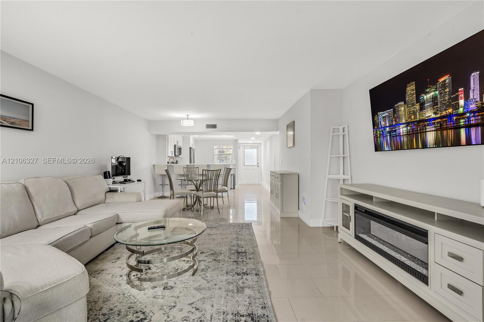 Open-concept interior featuring large-format tile flooring, recessed lighting, and a built-in electric fireplace unit