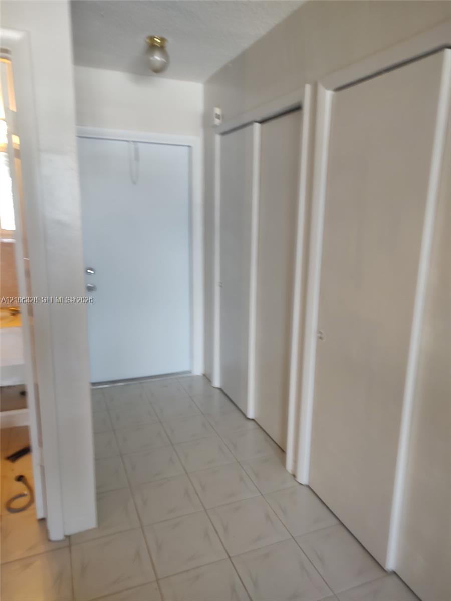 Entryway featuring light-toned tile flooring, dual-panel closet doors, and flush-mount lighting
