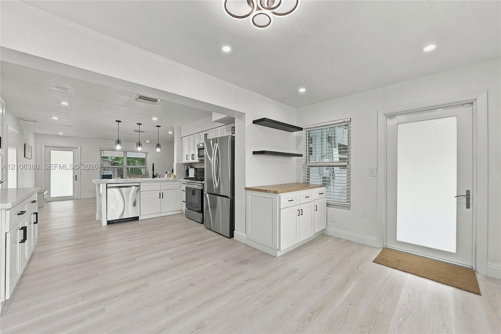 Kitchen featuring white cabinetry, stainless steel appliances, wood-finish flooring, recessed lighting, and a butcher-block countertop workspace with floating shelving