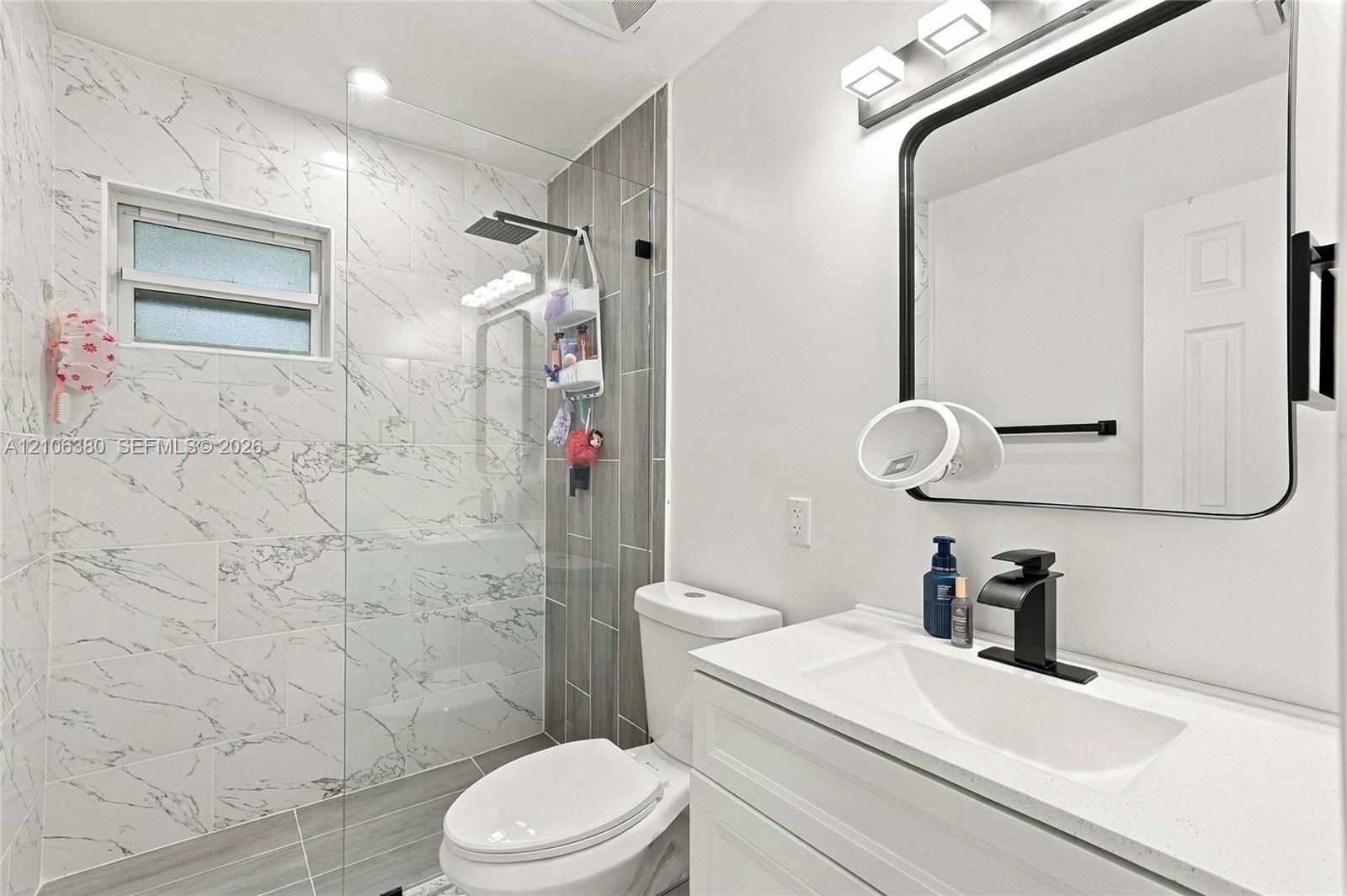 Bathroom featuring a vanity with a white composite countertop, integrated rectangular sink, and matte black faucet
