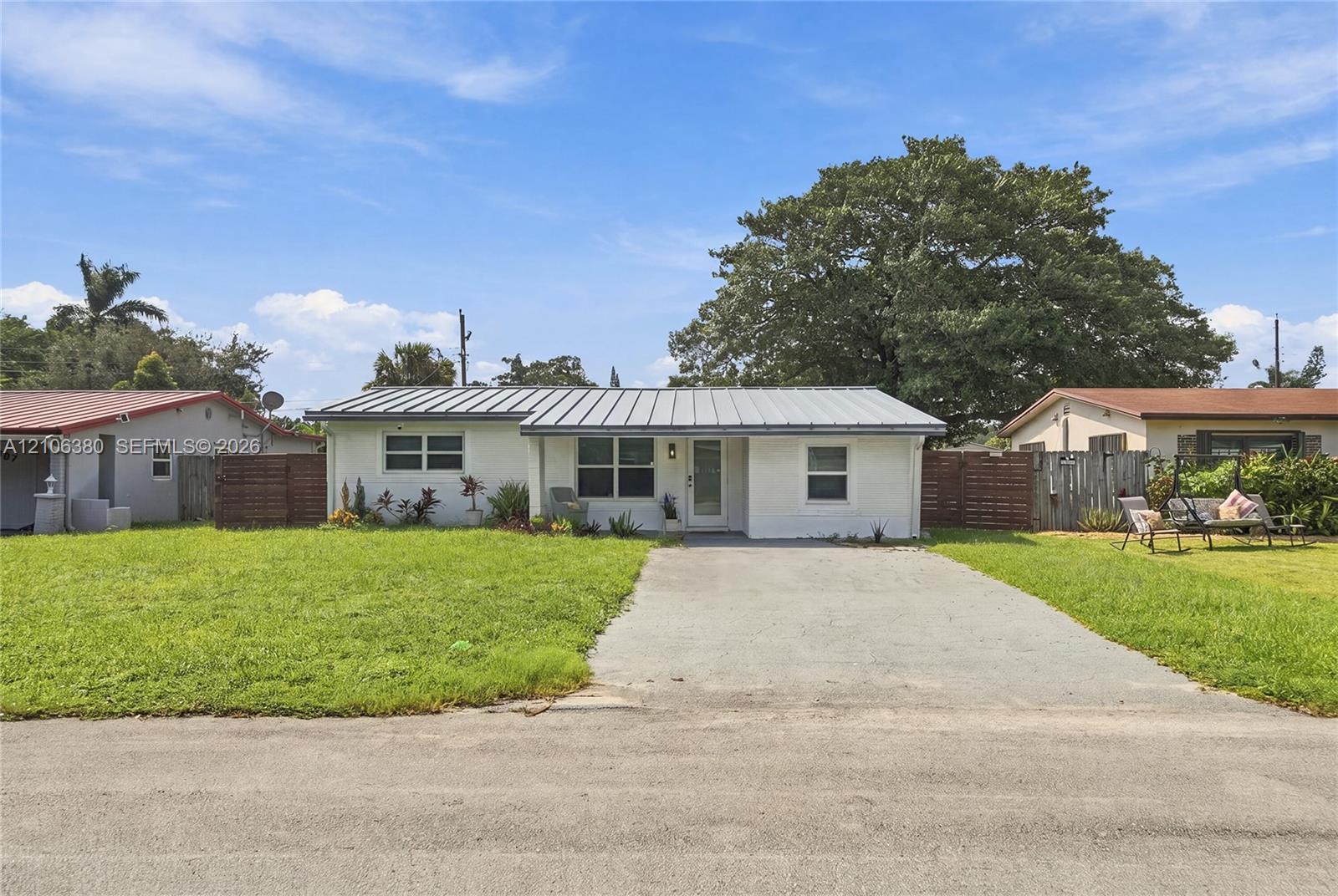 Single-story exterior featuring painted masonry siding, a standing-seam metal roof, and a concrete driveway Single-story exterior featuring painted masonry siding, a standing-seam metal roof, and a concrete driveway
