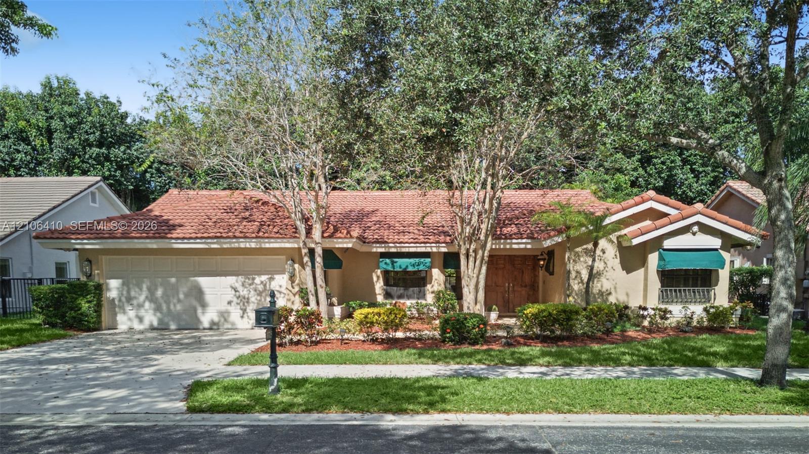 Single-story exterior featuring a clay tile roof, stucco facade, double-door entry, and an attached two-car garage