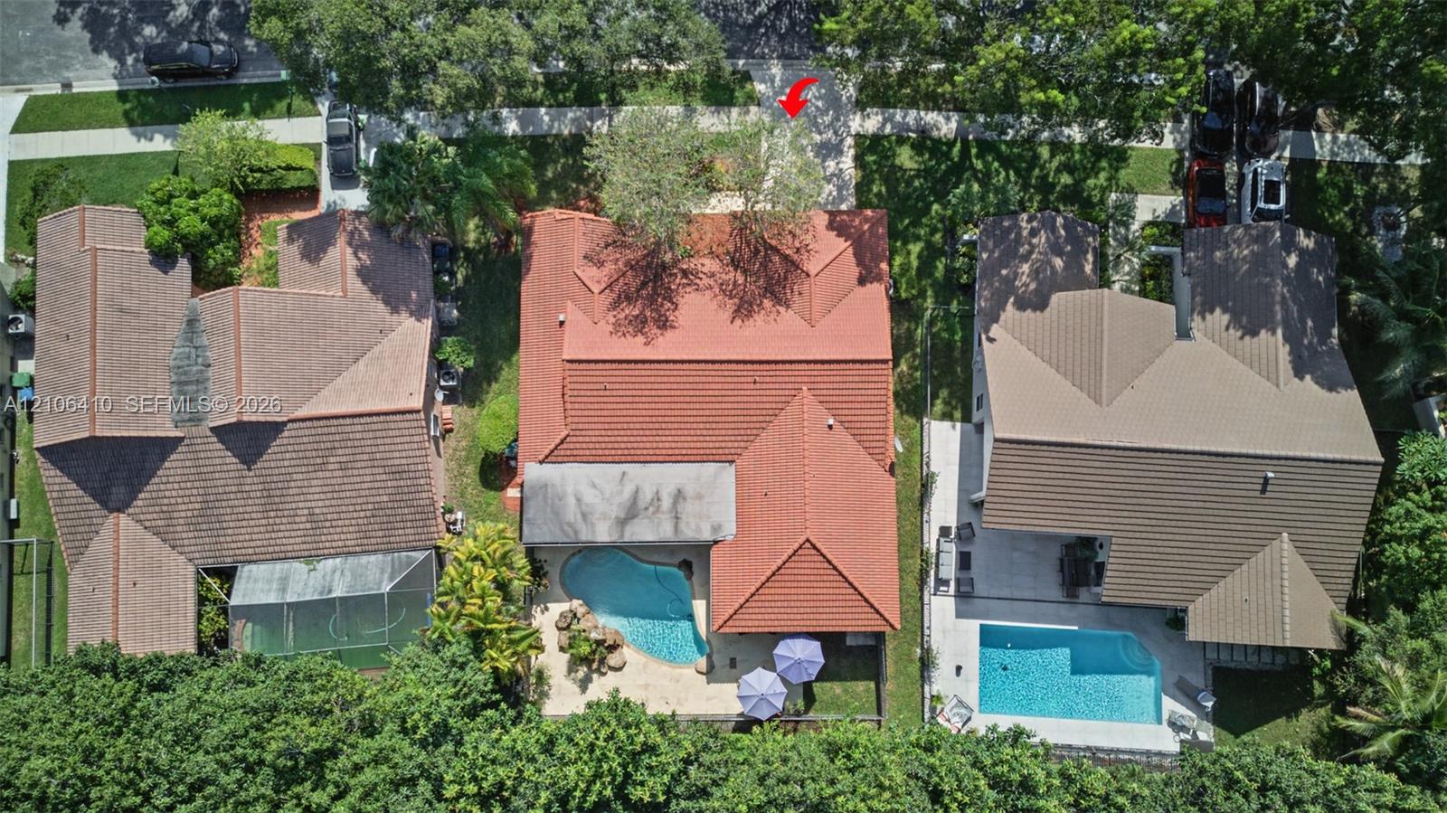 Aerial perspective of property featuring a tile roof, an in-ground swimming pool, and hardscaped patio area