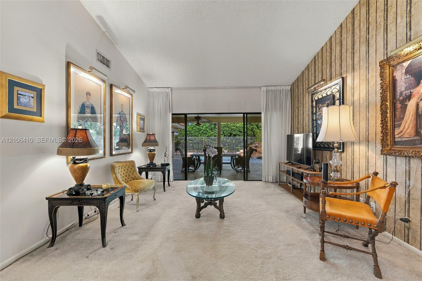 Living space featuring vaulted ceilings, floor-to-ceiling sliding glass doors, and decorative wall covering