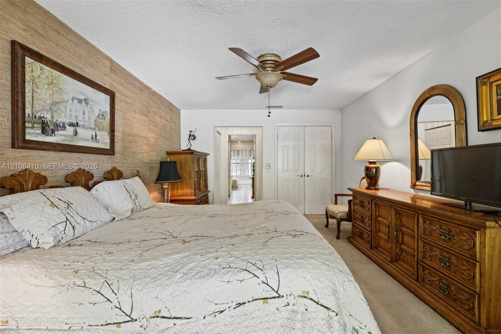 Textured wood-toned accent wall, ceiling-mounted fan with integrated lighting, and dual-panel closet doors