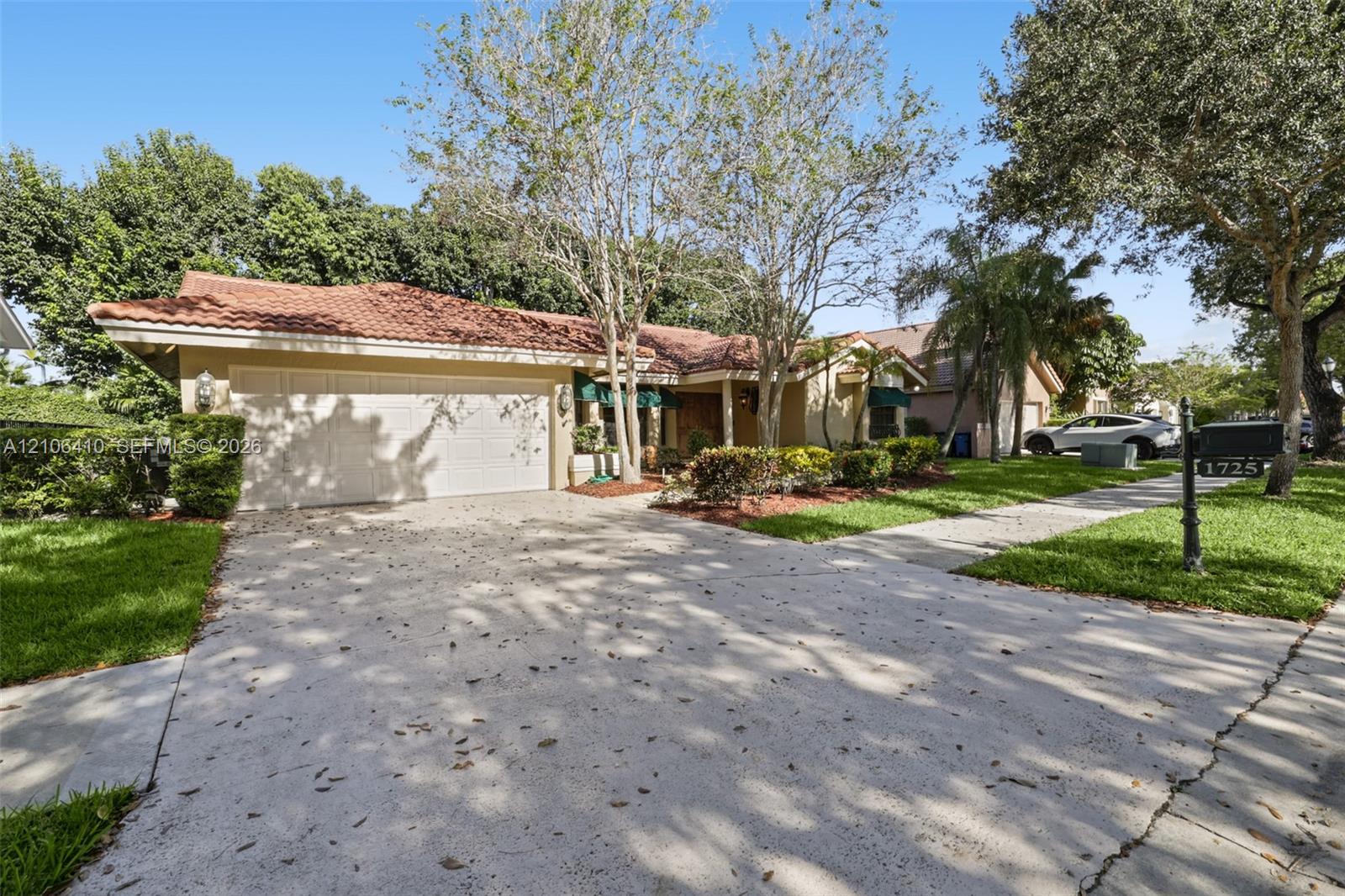 Single-story residence featuring a tile roof, light-toned stucco exterior, and a multi-car garage with a concrete driveway