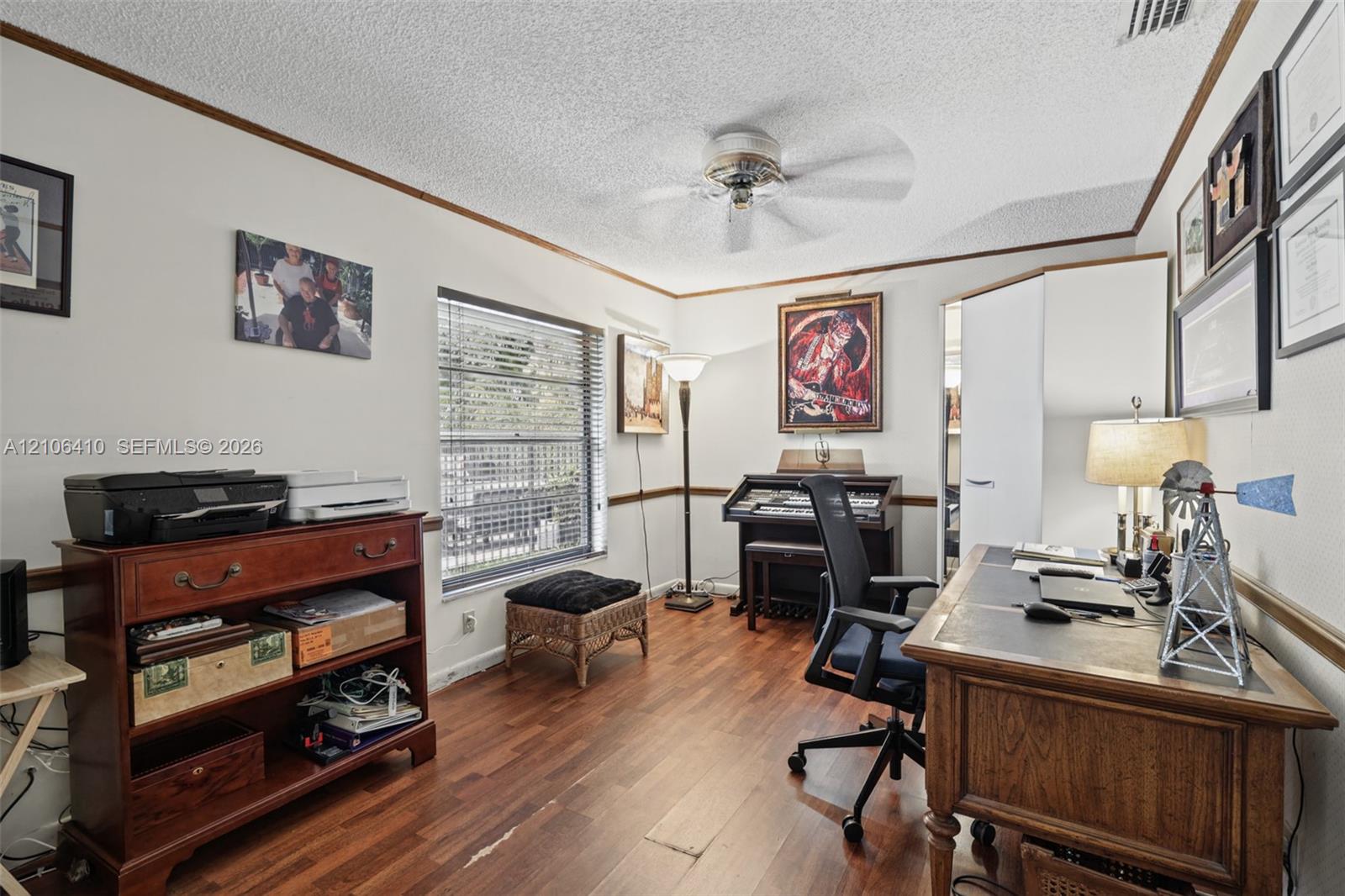 Wood-finish flooring, ceiling fan with integrated lighting, horizontal window blinds, and chair rail molding