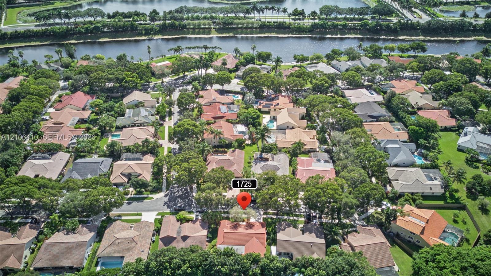 Aerial perspective of residential neighborhood featuring mature canopy trees, paved street grid, and bordering waterway