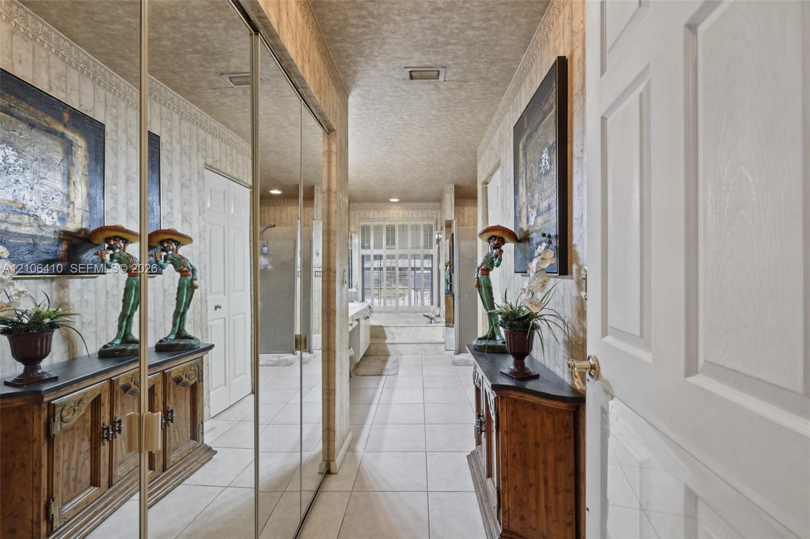 Hallway featuring full-height mirrored closet doors, tile flooring, crown molding, and a multi-pane window