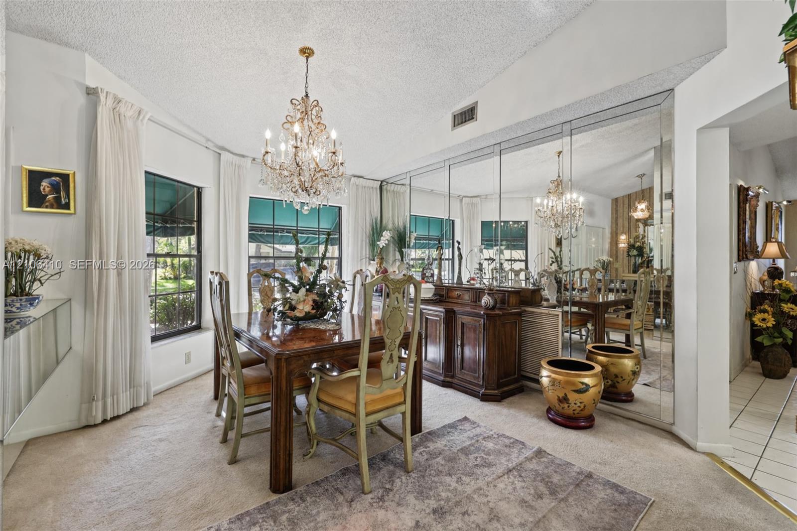 Dining area featuring vaulted ceilings, a decorative crystal chandelier, and a wall-to-wall mirrored accent wall