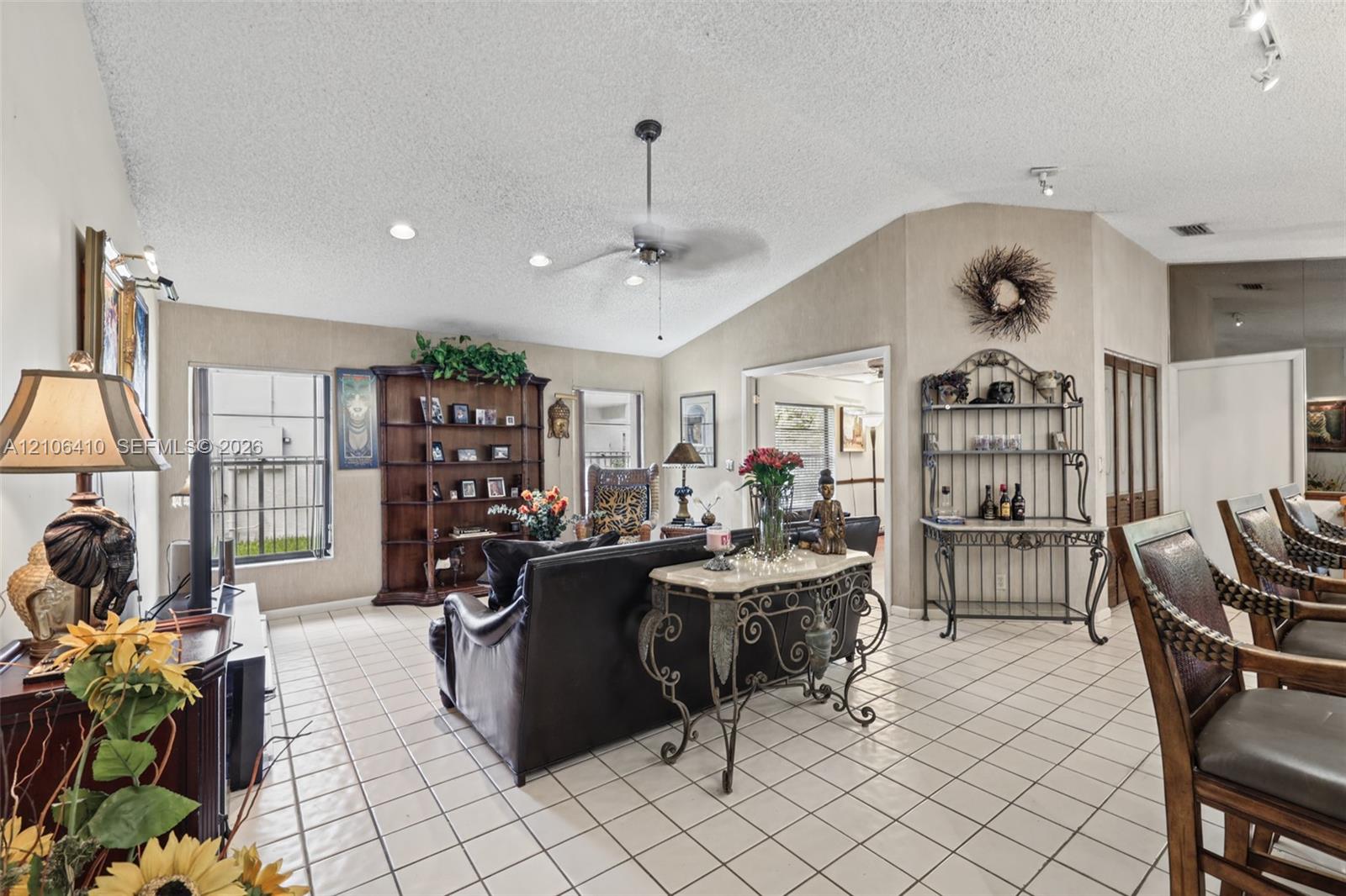 Living area featuring vaulted ceilings, ceramic tile flooring, built-in shelving, and a central ceiling fan
