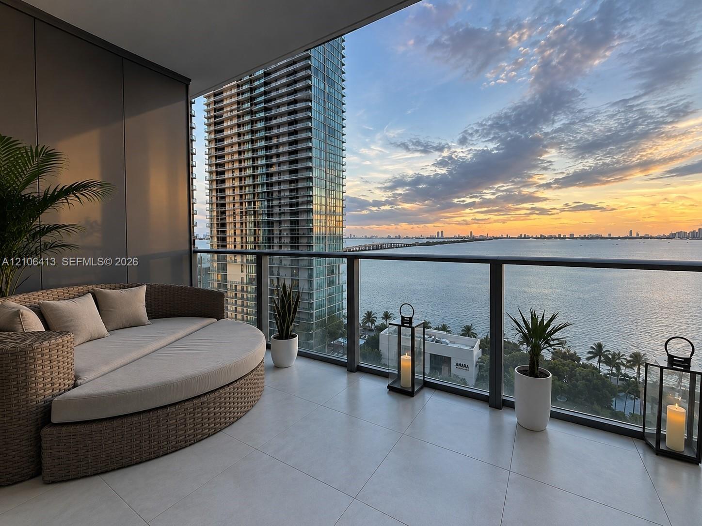 Private balcony featuring large-format tile flooring and a glass-paneled railing, overlooking open water and cityscape scenery