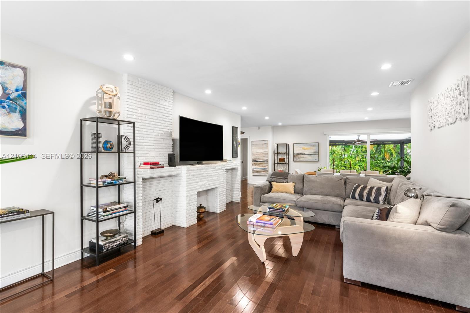 Living area featuring wood-finish flooring, recessed lighting, and a floor-to-ceiling white brick fireplace