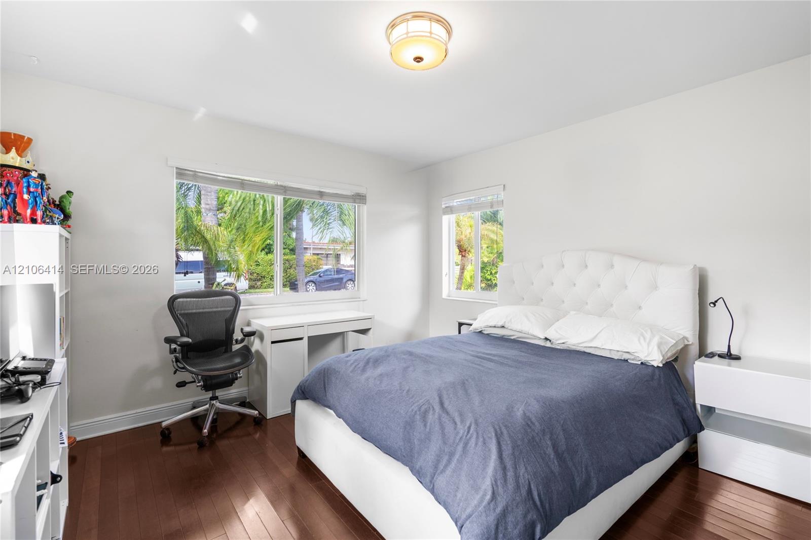 Bedroom featuring dark wood-finish flooring, dual windows, and a flush-mount ceiling light fixture