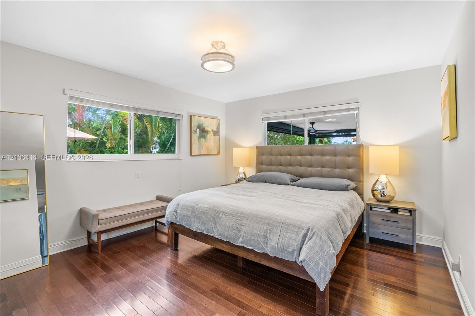 Wood-finish flooring, neutral wall tones, two large dual-pane windows, and a flush-mount overhead light fixture