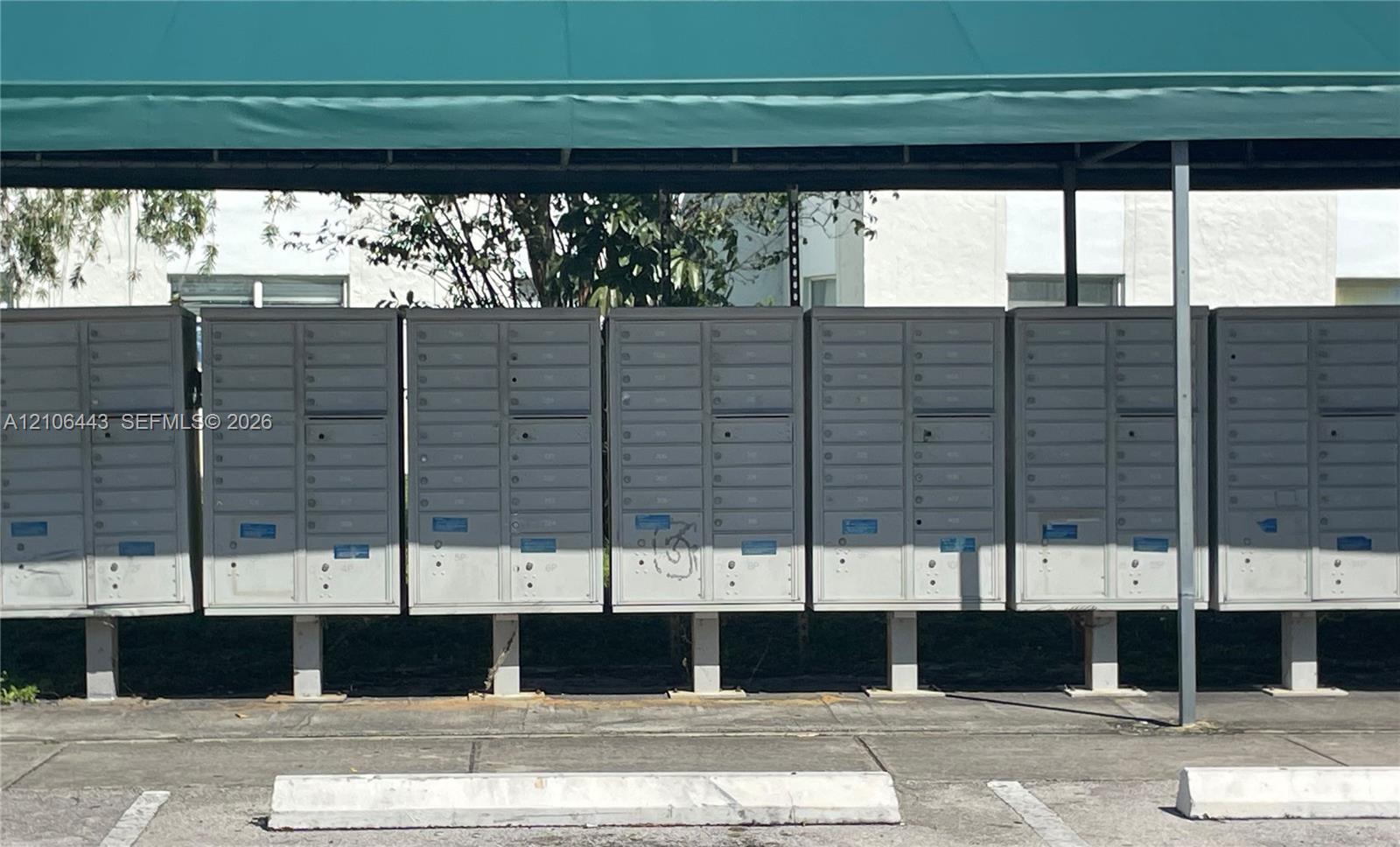Covered communal mail center featuring banks of individual locking mailboxes with metal construction and overhead canopy
