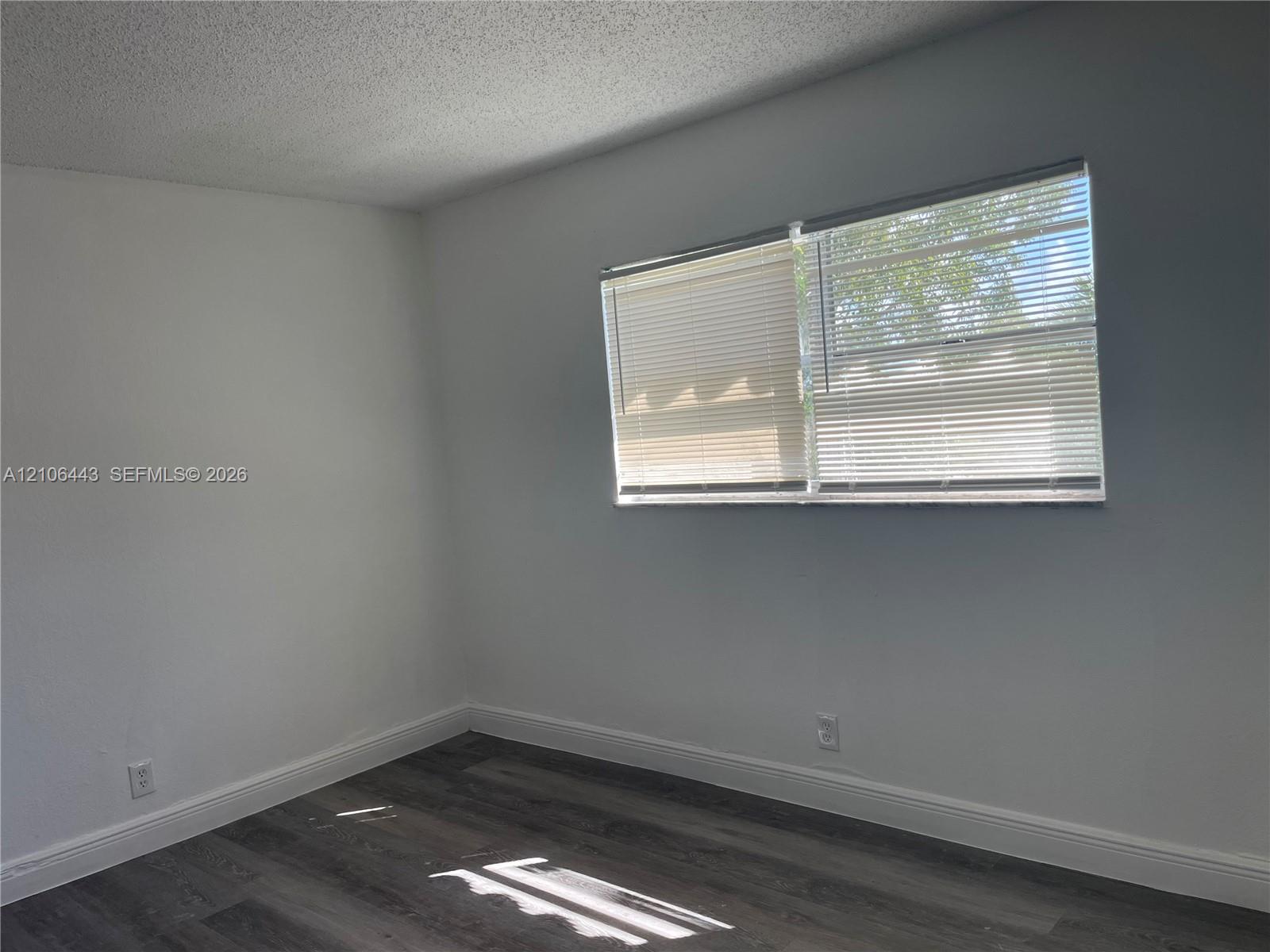 Neutral wall finishes, wood-finish flooring, and a window featuring horizontal blinds