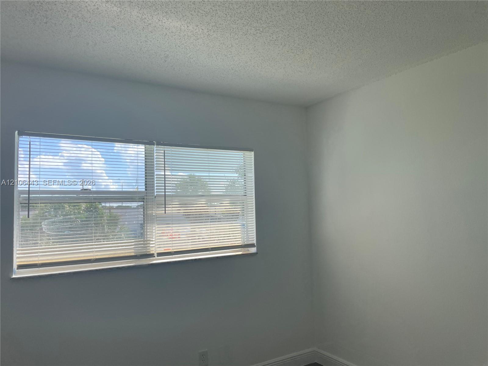 Interior space featuring neutral wall paint, textured ceiling, and a horizontal sliding window equipped with installed blinds