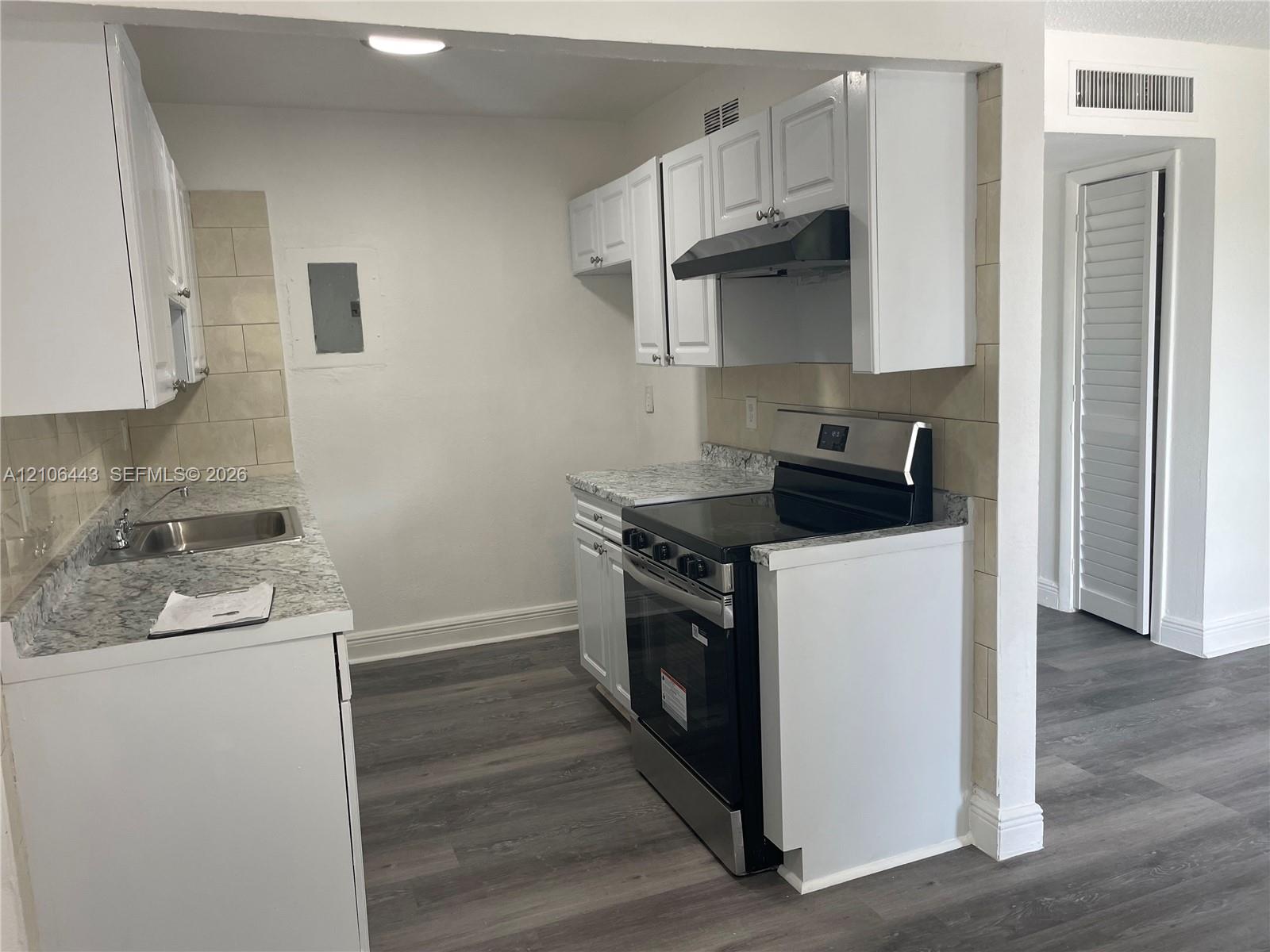 Kitchen featuring white cabinetry, stone-patterned laminate countertops, stainless steel range with integrated hood, stainless steel sink, and wood-finish flooring