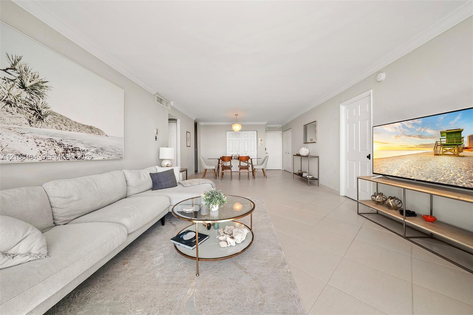 Open-concept interior featuring large-format neutral floor tile, crown molding, and recessed lighting