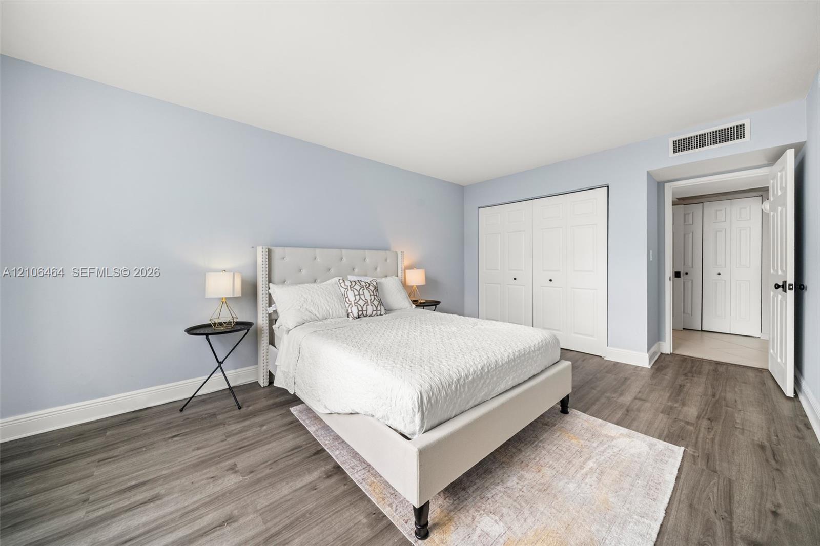 Bedroom featuring wood-finish flooring, soft-toned walls, and double-door closets