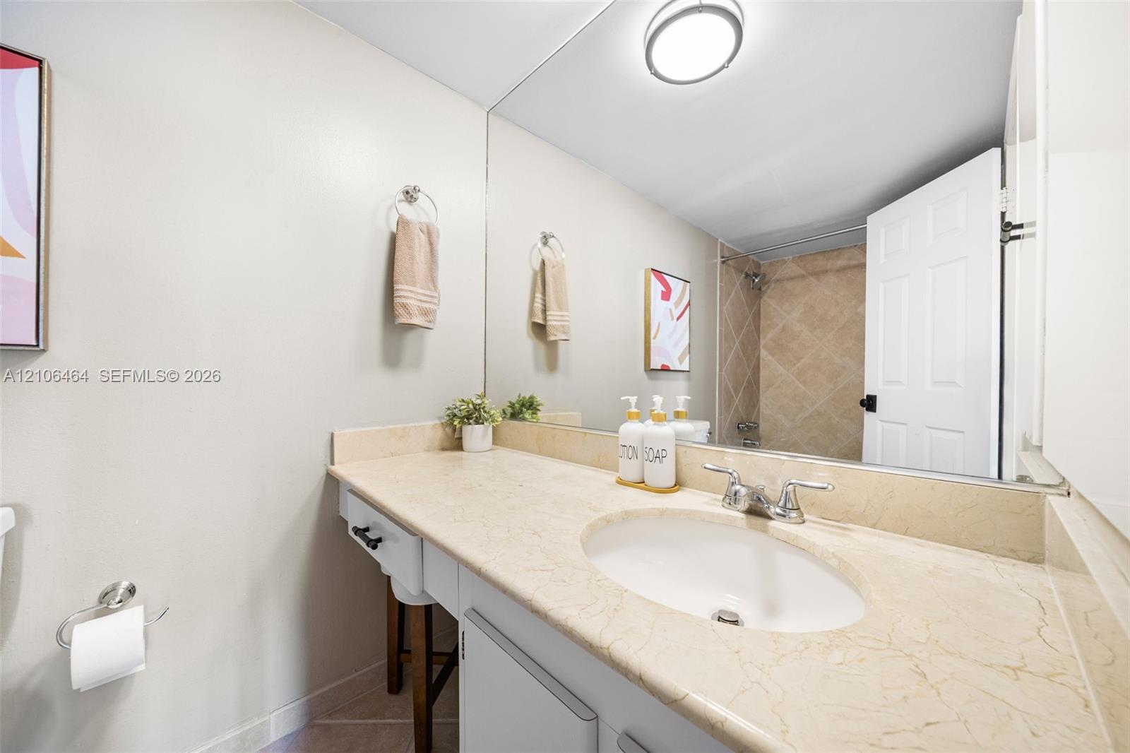Bathroom featuring a vanity with a stone countertop, oval undermount sink, full-width wall mirror, and a tiled shower surround