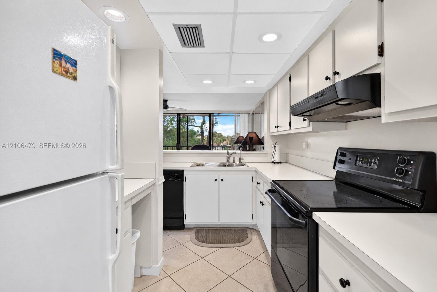 Kitchen featuring white cabinetry, contrasting black appliances, recessed lighting, and tile flooring