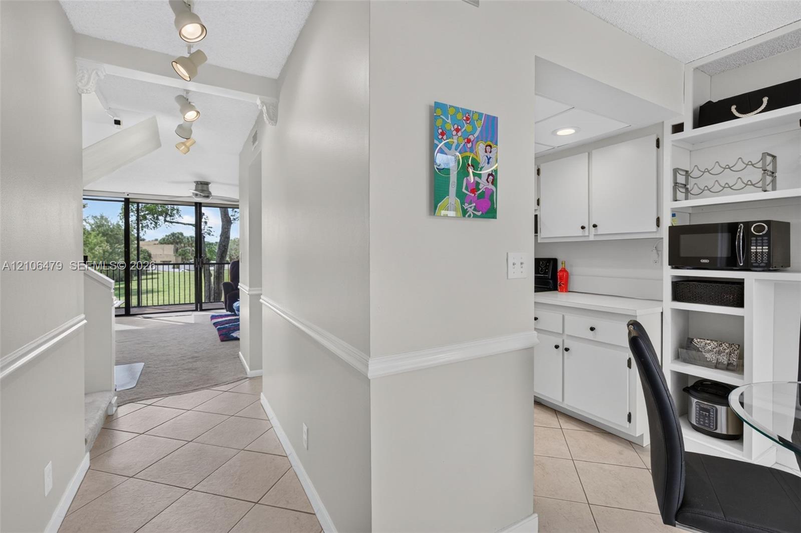 Tile flooring, track lighting, built-in cabinetry, and white shaker-style lower cabinets with a coordinating countertop