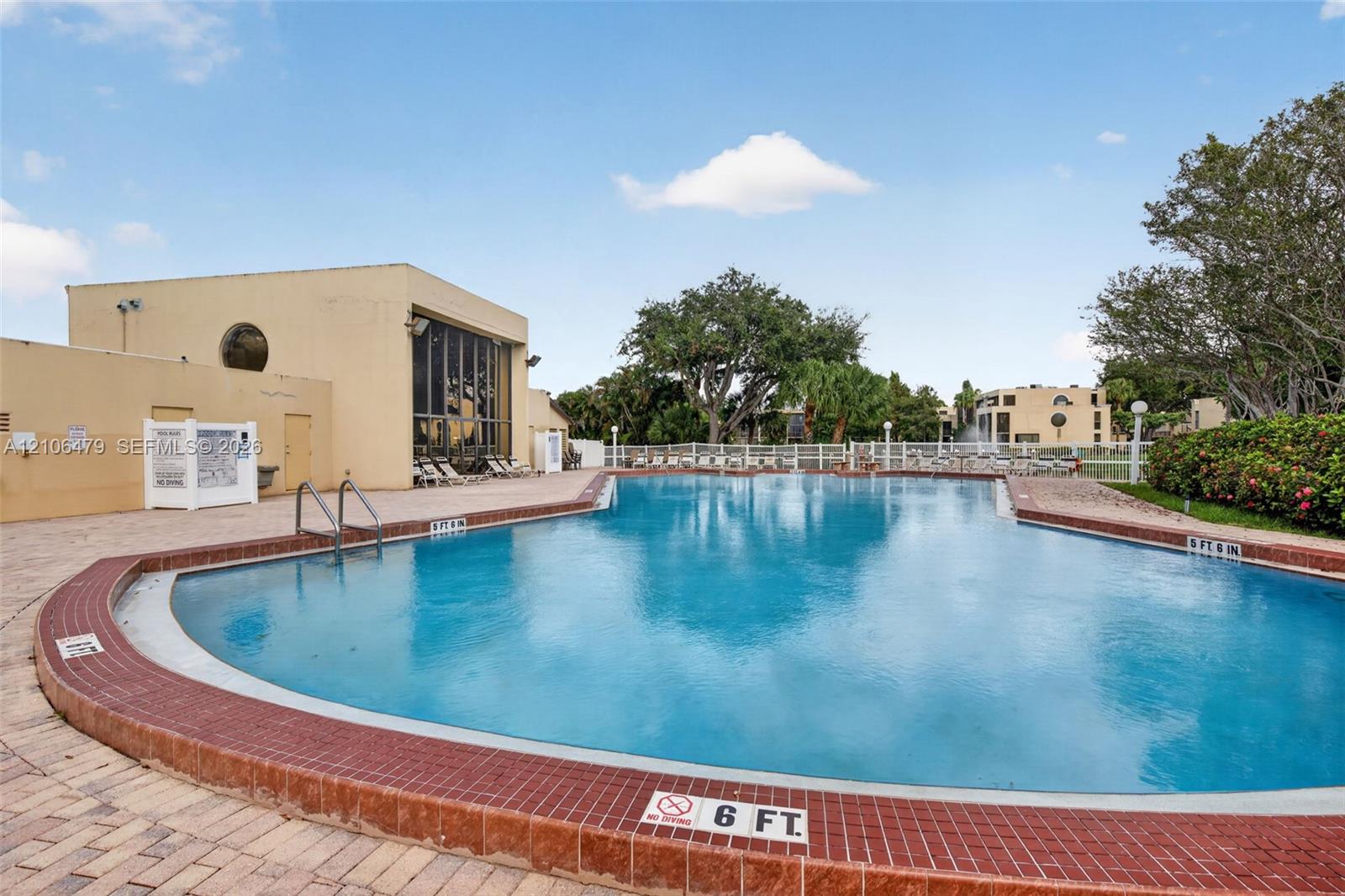 In-ground swimming pool featuring a brick-tiled coping, metal pool ladders, and stone-paver decking