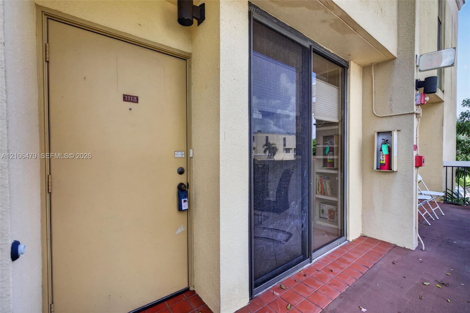 Exterior entryway featuring a solid-core door, sliding glass door with screen, stucco exterior wall finish, and tiled flooring