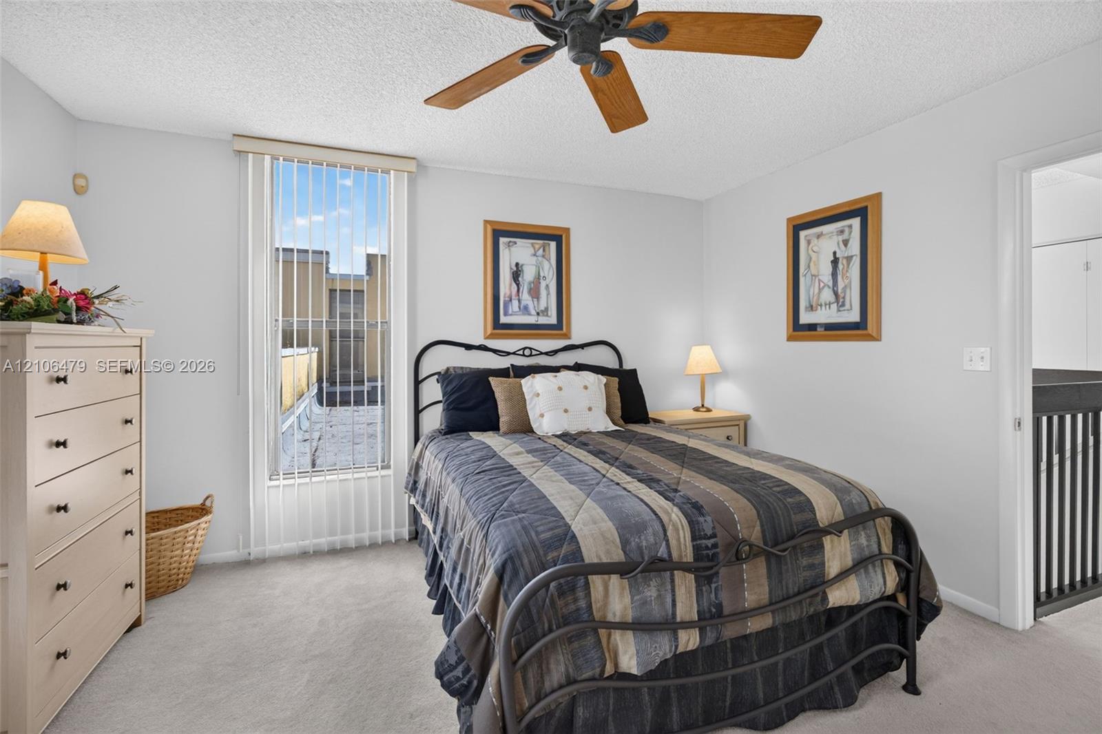 Bedroom featuring a tall vertical window with vertical blinds, carpeted flooring, and a ceiling fan with light fixture