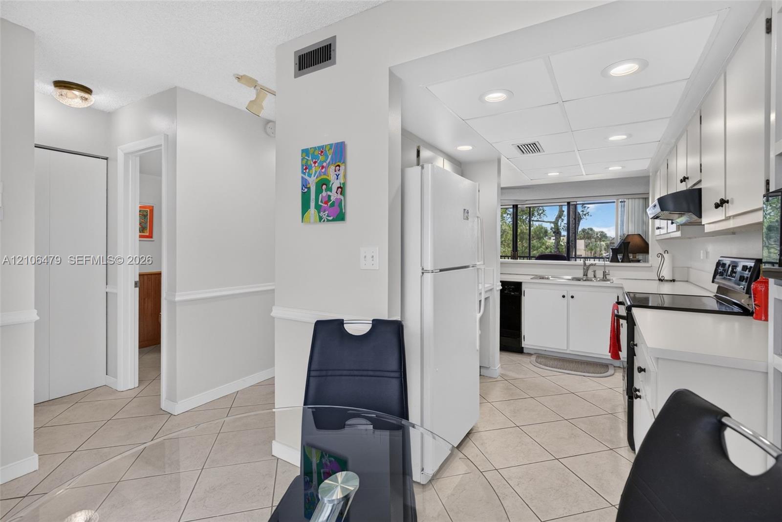 Kitchen featuring white cabinetry, integrated appliances, recessed lighting, and tile flooring