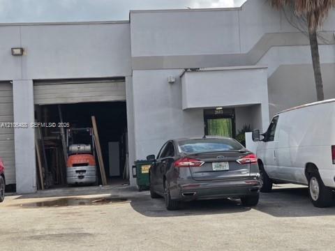 Industrial commercial property featuring concrete construction, overhead roll-up bay door, recessed entry, and exterior wall-mounted lighting