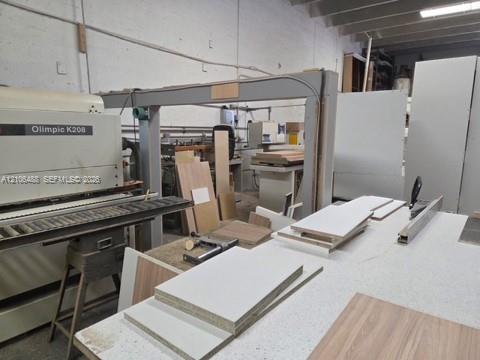 Industrial workspace featuring concrete walls, exposed ceiling joists, and integrated cabinetry production machinery