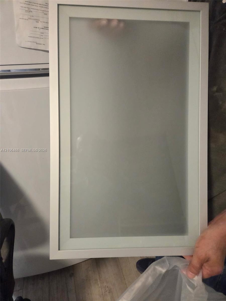 Rectangular cabinet door featuring a slim metallic frame with a centered frosted glass panel