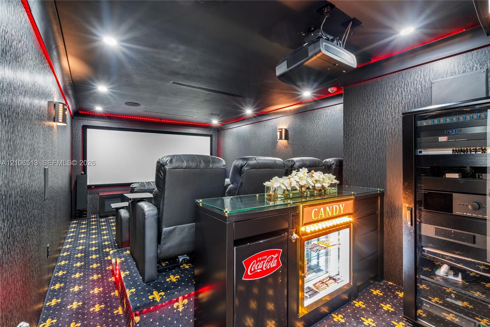 Dedicated media room featuring a large projection screen, recessed lighting, integrated ceiling-mounted projection equipment, and a built-in equipment rack