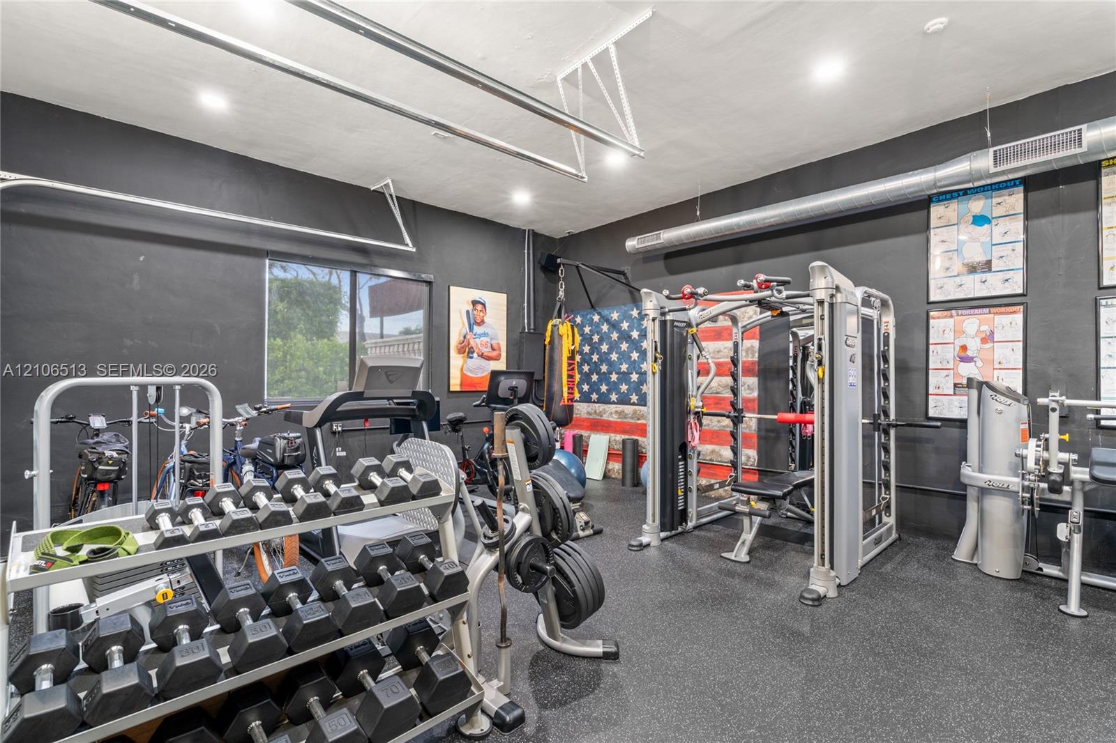 Finished garage space featuring matte black wall paint, rubberized flooring, exposed metal ductwork, and recessed lighting