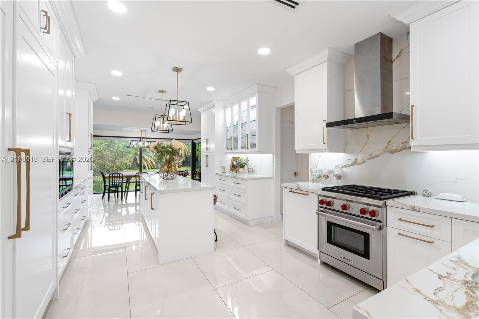 Kitchen featuring white Shaker-style cabinetry, a central island with a stone-finish countertop, stainless steel professional-grade range, full-height stone-finish backsplash, and polished tile flooring