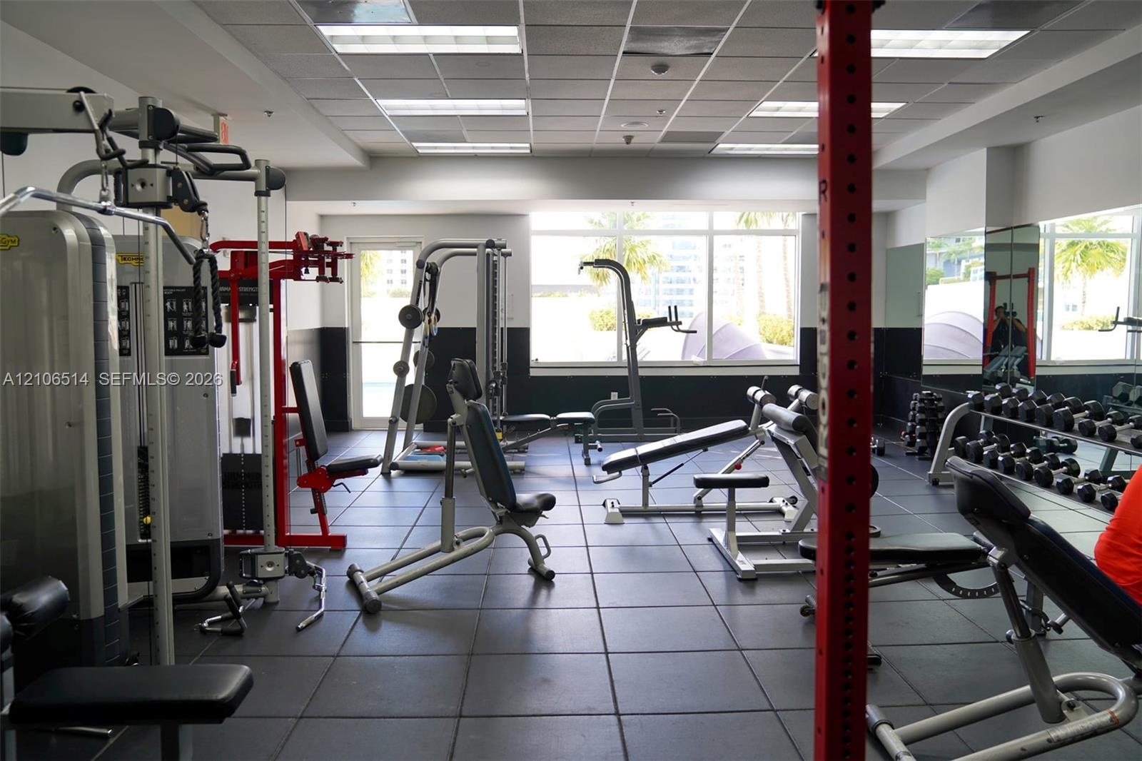 Fitness room featuring impact-resistant rubber flooring, floor-to-ceiling windows, and recessed ceiling panels