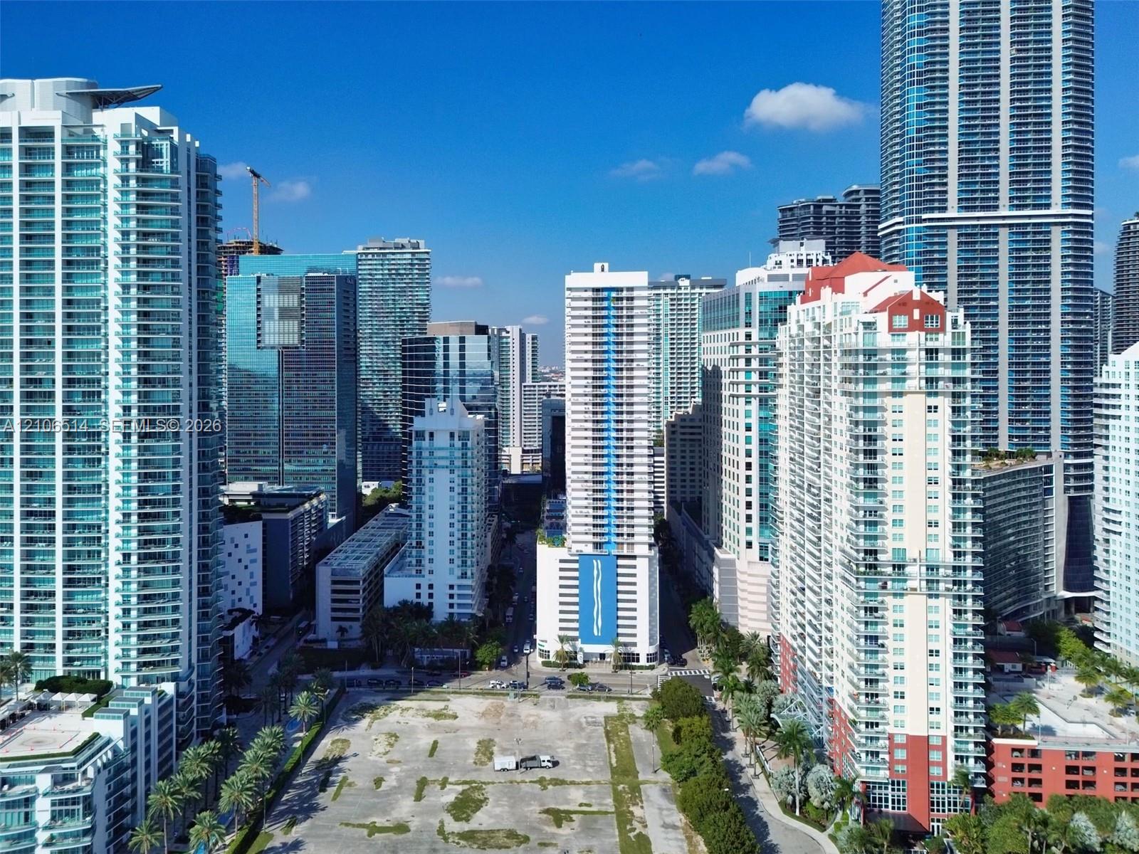 Aerial perspective featuring high-density urban infrastructure, surrounding glass-facade skyscrapers, and a central cleared parcel