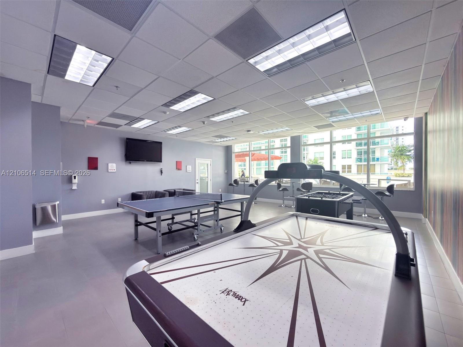 Recreation room featuring a drop ceiling with recessed rectangular lighting, large windows, and smooth-finish flooring
