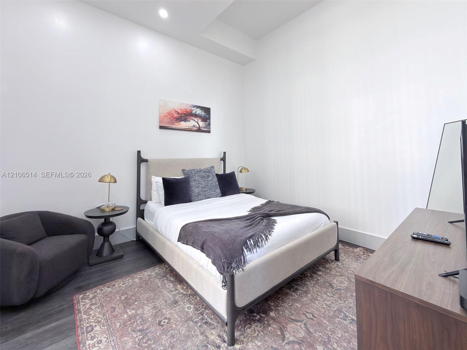 High-ceiling bedroom featuring dark wood-finish flooring and recessed lighting