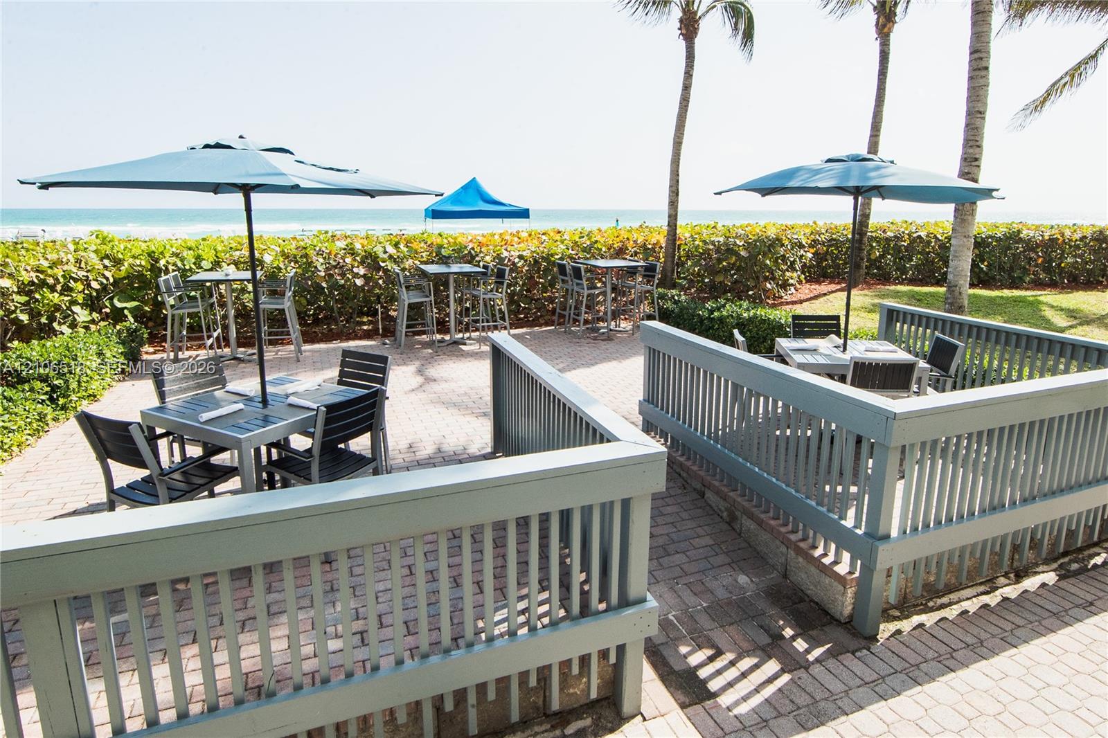 Paver patio featuring perimeter railings and mature palms with ocean frontage