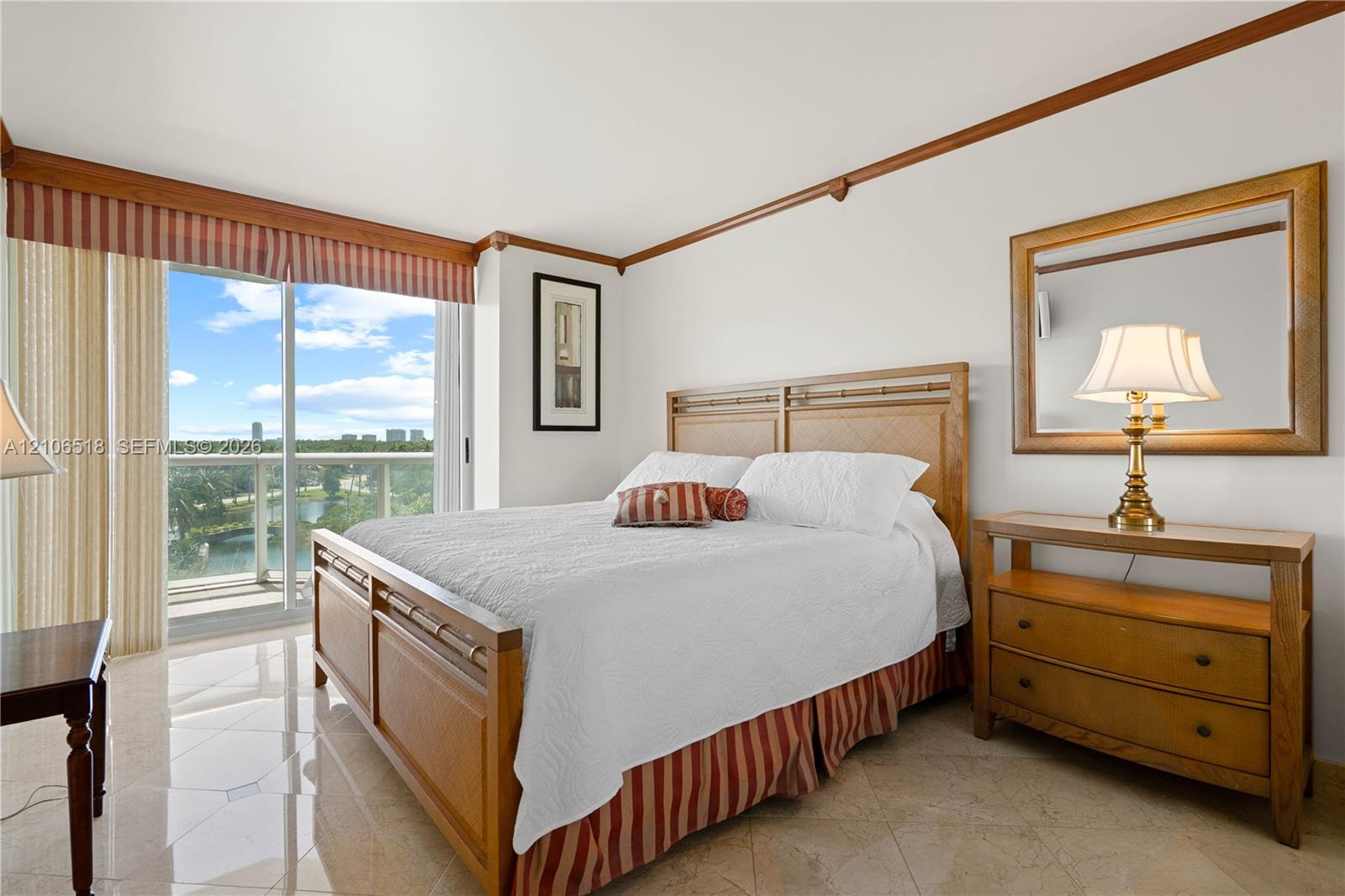 Polished stone flooring, crown molding, and sliding glass doors with balcony access