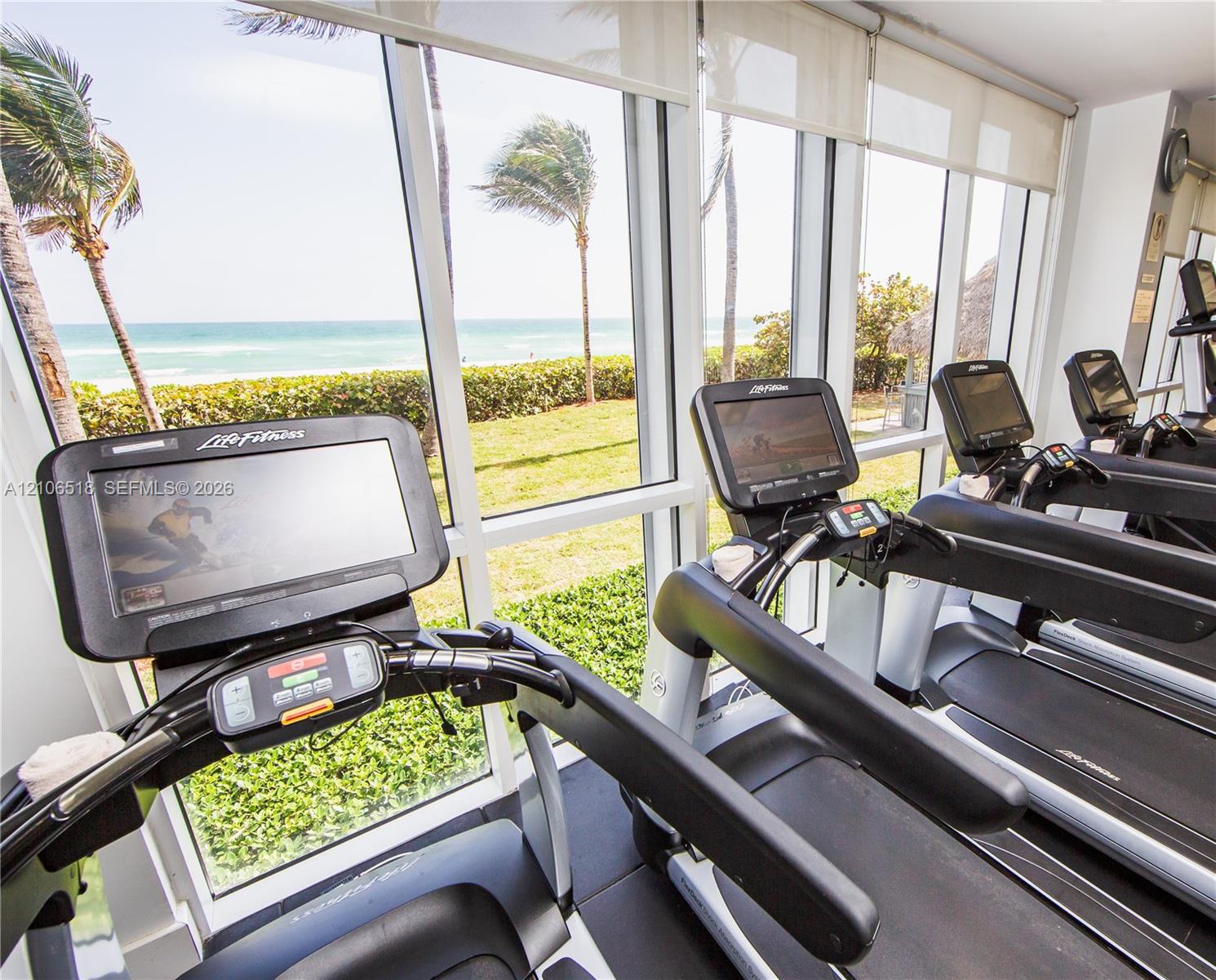Floor-to-ceiling windows, ocean horizon backdrop, and fitness center with professional-grade equipment