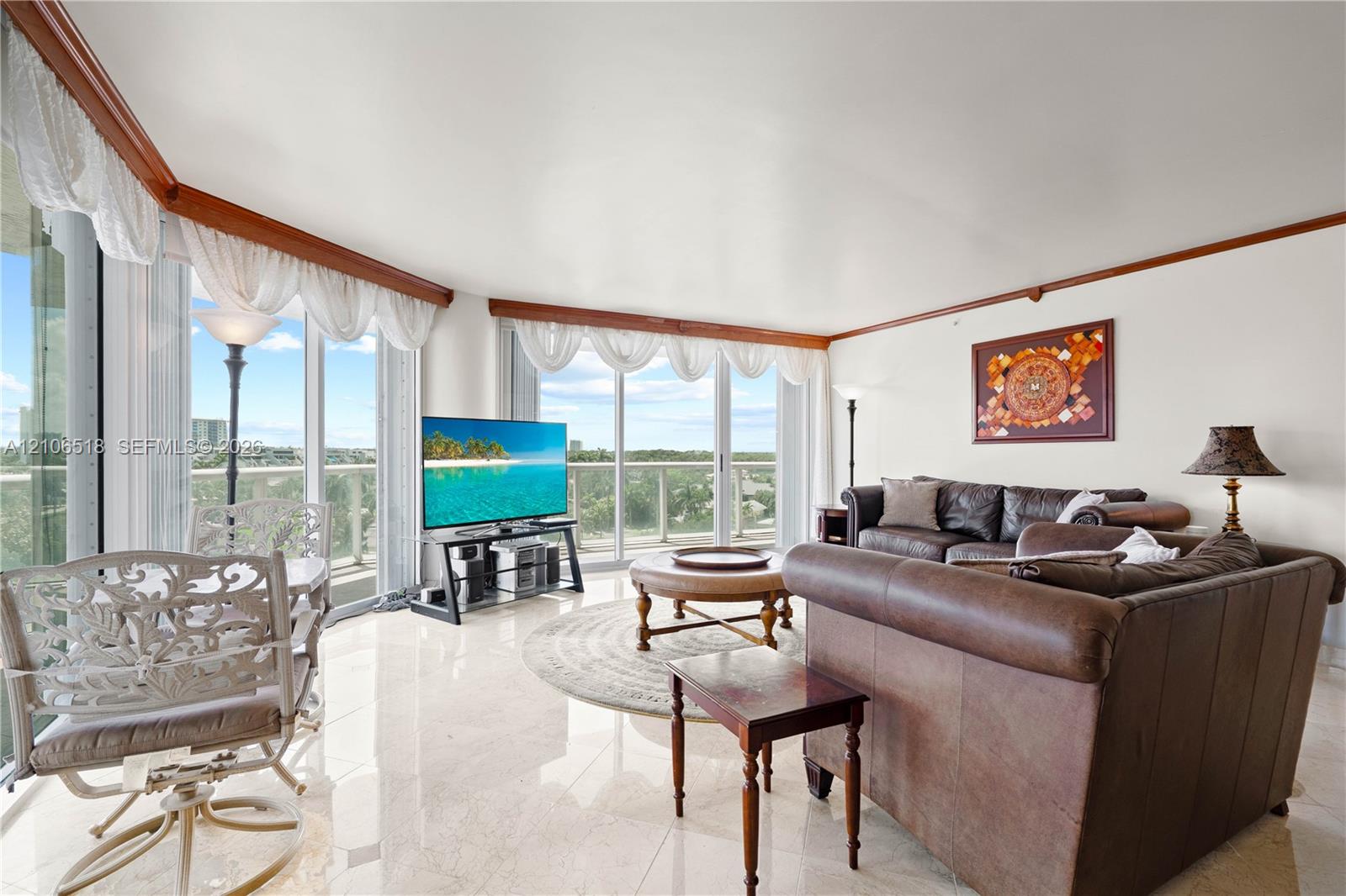 Living area featuring polished stone tile flooring, floor-to-ceiling glass walls, and crown molding